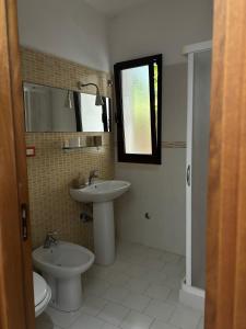 a bathroom with a sink and a toilet and a mirror at L'Asfodelo in Uggiano la Chiesa +6 photos