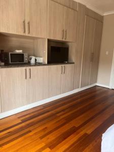 an empty kitchen with wooden floors and a microwave at At Sta-Plus Guest House in Port Elizabeth +21 photos