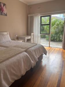 a bedroom with a large bed and a large window at At Sta-Plus Guest House in Port Elizabeth