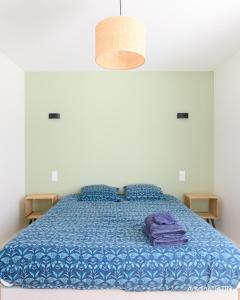 a bedroom with a bed with a blue comforter at Barbâtre Les Figuiers Plage à 500 m in Barbâtre