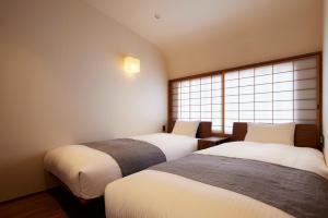 two beds in a room with a window at Minn Nijo-jo in Kyoto
