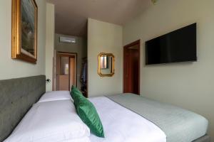 a bedroom with two white beds and a flat screen tv at Dimore Morelli Brescia in Brescia