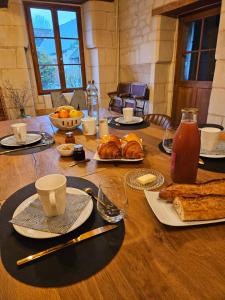 a wooden table with food and bread on it at Au pied du Lavoir chambre Germaine in Grézillé