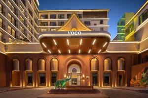 景洪市voco 西双版纳告庄voco酒店的一座建筑前面有恐龙雕像