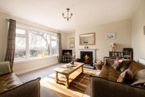 een woonkamer met een bank en een open haard bij Kirktoun Cottage in Duffus