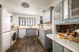 een grote keuken met blauwe kasten en witte apparaten bij Kirktoun Cottage in Duffus