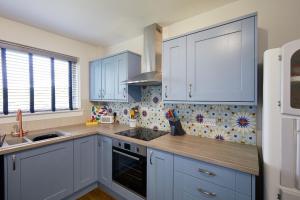 een keuken met witte kasten en een spoelbak bij Kirktoun Cottage in Duffus