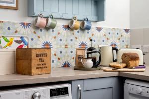 een keuken met een aanrecht met koffiekopjes en brood bij Kirktoun Cottage in Duffus