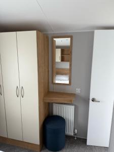 a room with a mirror and a cabinet and a stool at Glenlea in Selsey