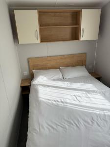 a bedroom with a white bed with a wooden headboard at Glenlea in Selsey +1 photo