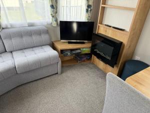 a living room with a couch and a flat screen tv at Glenlea in Selsey