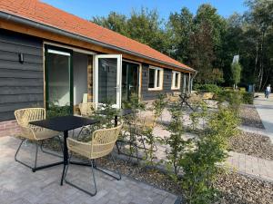 a patio with a table and chairs in front of a building at HoeveLieshout - Lux 4 persoons platteland appartement in Weert