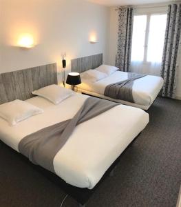 two beds in a hotel room with two bedsskirts at Hôtel Le petit billot in Vitré