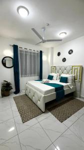 a bedroom with a large white bed with blue sheets at Pinkys Cozy Home in Mombasa
