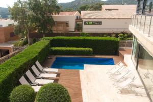 Un patio con sillas blancas y una piscina. en WELCS VILLA 239 PDA con piscina y vista, en Sant Feliu de Guíxols