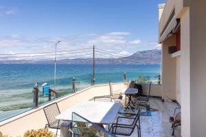 ein Balkon mit Tisch und Stühlen und dem Meer in der Unterkunft LIVAS Corinth Seaside Family Apartment in Kórinthos