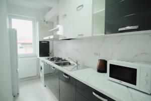 a white kitchen with a sink and a microwave at JAY House Radauti in Rădăuţi