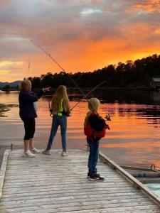 three people standing on a dock fishing on a lake at Draget gård, idyllisk småbruk ved sjøen in Molde