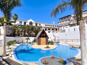 a hotel with a swimming pool and palm trees at RenTenerife Magec Swing & Sun Amarilla Golf in San Miguel de Abona