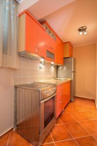 een keuken met oranje kasten en een koelkast bij Apartments Mika in Budva