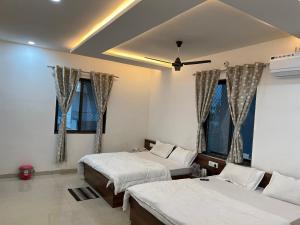 KhātuHotel Shri Raghuvansh的有两张床和两扇窗户的卧室