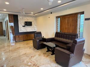 a waiting room with a couch and a tv at hOTEL MADHAVA RESIDENCY in Kākināda