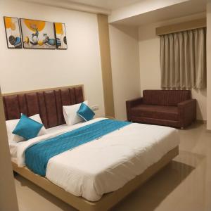 Un dormitorio con una cama grande y una silla. en Hotel Krishna Park, en Anand