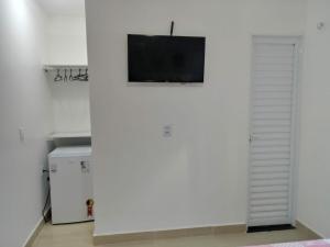 a living room with a tv on a white wall at Kitnet de luxo perto do shopping da ilha in São Luís