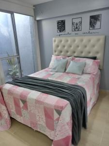 a bedroom with a bed with a pink and white bedspread at Kitnet de luxo perto do shopping da ilha in São Luís