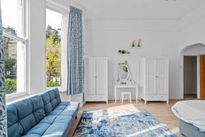 Una sala de estar con un sofá azul y una ventana. en Charming 3BR by Redcliffe Gdns, en Londres