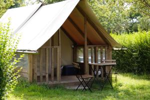 a gazebo with a table and chairs in the grass at Camping Onlycamp Sous les Pommiers in Trévières