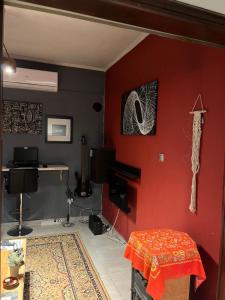 Una sala de estar con una pared roja con un escritorio. en Cozy and modern apartment, en Corfú