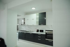 a kitchen with black cabinets and white appliances at JAY House Radauti in Rădăuţi