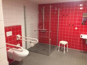 Un baño rojo con ducha y WC. en Jugendherberge Berlin - Am Wannsee, en Berlín