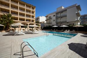 a swimming pool with chairs and umbrellas next to a building at Apartamentos Isla del Sol in Can Pastilla