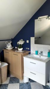 Łazienka z białą umywalką i niebieską ścianą w obiekcie Appartement Vallée de la Risle w mieście Glos-sur-Risle