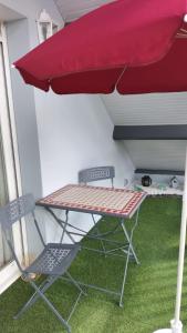 stół i krzesło pod czerwonym parasolem w obiekcie Appartement Vallée de la Risle w mieście Glos-sur-Risle