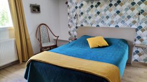 sypialnia z niebieskim łóżkiem z żółtą poduszką w obiekcie Appartement Vallée de la Risle w mieście Glos-sur-Risle