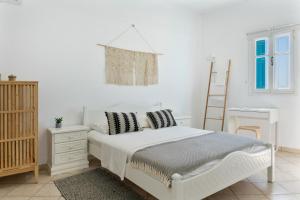 a white bedroom with a white bed and a ladder at Olympos Blue in Olympos