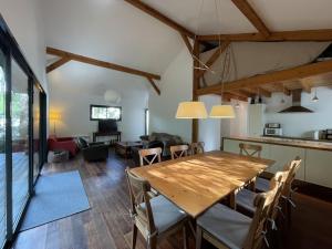 a dining room and living room with a wooden table and chairs at Villa 8 pers. Soustons proche lac, océan et golf, WiFi, animaux admis, parking - FR-1-379-83 in Soustons
