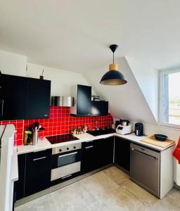 a kitchen with black cabinets and a red tile wall at Le Molay in Beaune