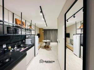 a kitchen with black and white counters and a table at Edifício Box 150 - LikeHome Hospedagens in João Pessoa