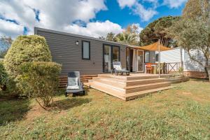 ヴァンドルにあるCamping Domaine de la Yoleの椅子2脚付きのデッキを備えたモジュラー住宅