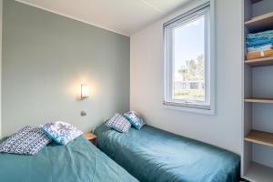 ヴァンドルにあるCamping Domaine de la Yoleの窓のある部屋にベッドが2つある +26枚の写真