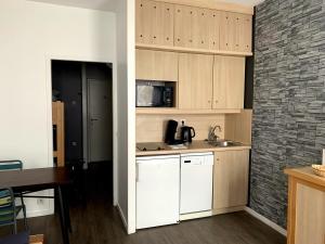 a kitchen with white cabinets and a brick wall at Studio dans une residence hoteliere avec piscine couverte in La Rochelle
