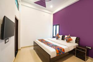 a bedroom with a bed with purple walls and a tv at Via Awadh Royal in Ayodhya