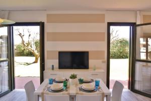 a dining room with a table and a tv at Appartamenti in Residence Portosole e Residence Tamerici con piscina-Cavallino Treporti in Cavallino-Treporti