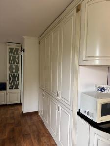 a kitchen with white cabinets and a microwave at 2к комнатная Квартира в центре размещение до 2х человек in Shymkent