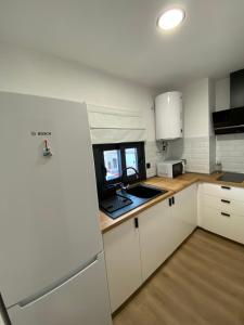 a kitchen with white cabinets and a laptop on the counter at Casa Mateo in Jedula