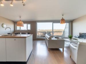 a kitchen and living room with white cabinets and a table at Apartment Albatros with parking by Interhome in Bredene +24 photos